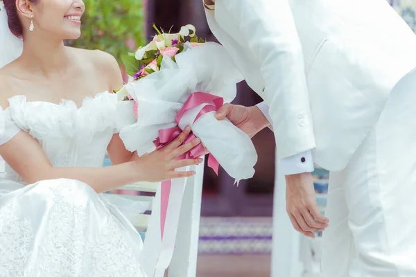 Casal segurando um buquê de flores com um feliz dia de casamento — Fotografia de Stock