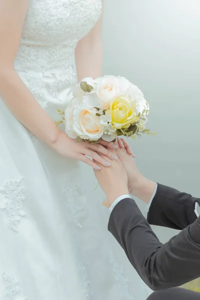Gift bruden och brudgummen hålla hand med en bukett blommor Stockbild