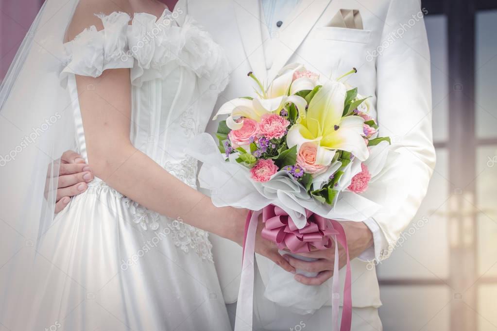 Couple holding a bouquet of flowers with a happy wedding day 