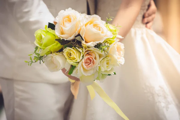 Novia y novio tomados de la mano y un ramo de flores como un toke —  Fotos de Stock