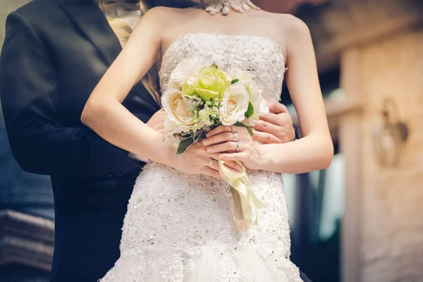 Sposa e sposo si tengono per mano e un mazzo di fiori come un toke — Foto Stock