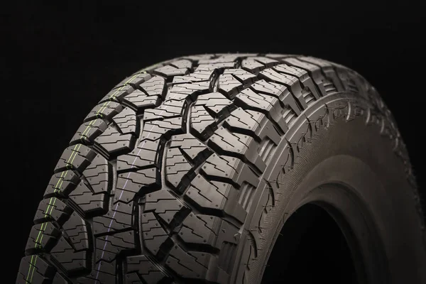 mud all terrain tires for SUVs on a black background close-up, slats and ground hooks, drainage channels and drawing checkers