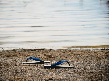 Terlikler gölün kenarına yerleştirilmiş boşanma ve kırık kalp konsepti.