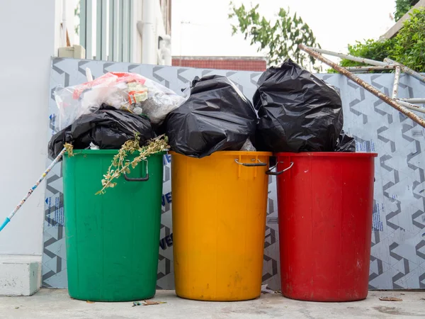 Green, yellow, and red bins that are full of trash