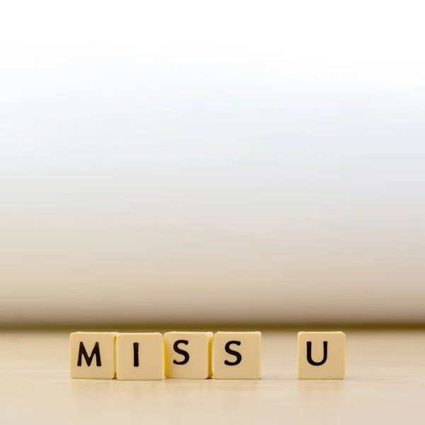 miss you word written in  cube on wooden floor on white background, letter blocks arranges into MISS U words, for adding text or other images or design