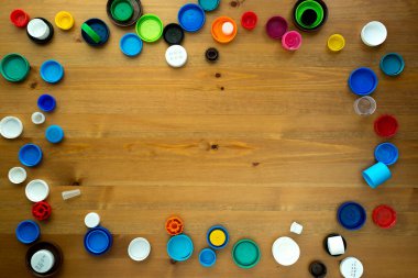 Ahşap arka planda plastik şişe kapakları. Kapak malzemesi geri dönüştürülebilir. Çevre koruma ve ekoloji kavramı
