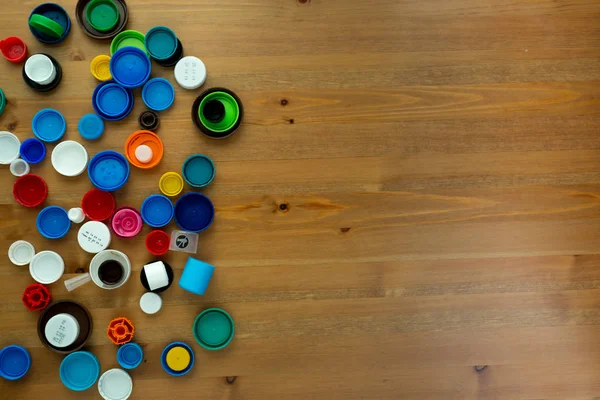 Ahşap arka planda plastik şişe kapakları. Kapak malzemesi geri dönüştürülebilir. Çevre koruma ve ekoloji kavramı