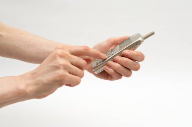 Bir kadın beyaz arka planda elinde eski model bir cep telefonu tutuyor.