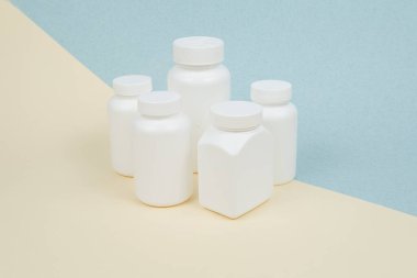 Sarı-mavi zemin üzerinde tablet veya kapsüller için beyaz plastik kaplar seti