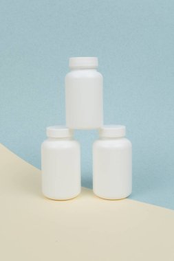 Sarı-mavi zemin üzerinde tablet veya kapsüller için beyaz plastik kaplar seti