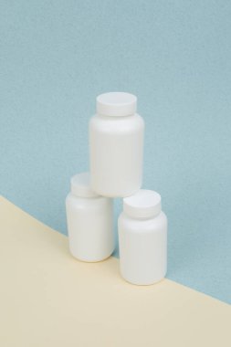 Sarı-mavi zemin üzerinde tablet veya kapsüller için beyaz plastik kaplar seti