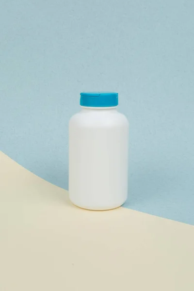 Sarı-mavi arka planda tablet veya kapsüller için beyaz plastik tıbbi kap