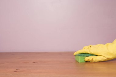 Eldivenli bir el masayı dezenfekte eder. Dezenfeksiyon ve hijyen konsepti, salgın ve daha fazlası bağlamında.