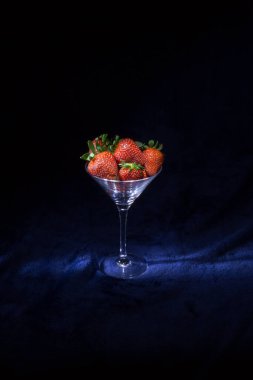Koyu arkaplanda bardakta çilek. Siluet biçimi.
