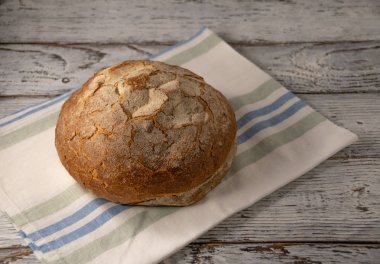 yuvarlak kahverengi ekmek beyaz keten peçete üzerinde eski ahşap arka planda