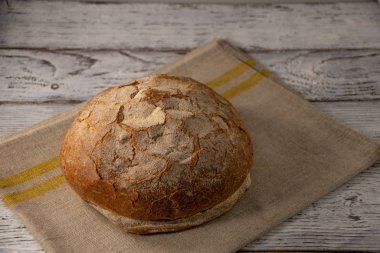 Eski ahşap arka planda gri keten peçetede taze kahverengi ekmek.