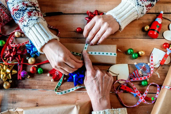 Händerna på två kvinnor inslagning julklappar. — Stockfoto