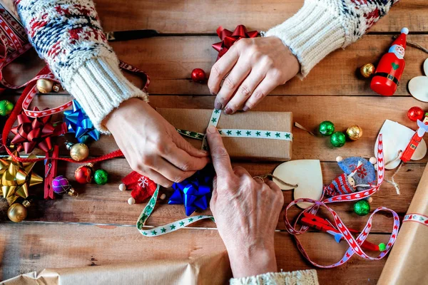 Handen van twee vrouwen inwikkeling Kerstcadeaus. — Stockfoto