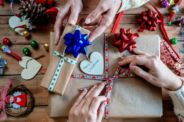 Händerna på två kvinnor inslagning julklappar — Stockfoto