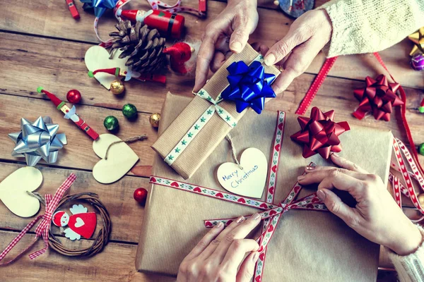 Mains de deux personnes enveloppant des cadeaux de Noël — Photo