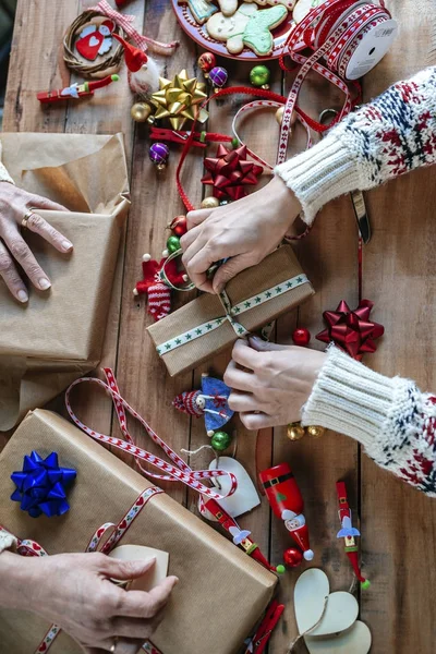 Händerna på två personer inslagning julklappar Stockbild