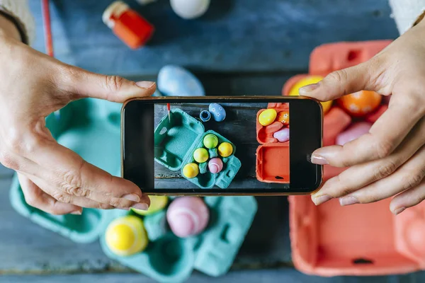 Woman taking a picture with the smartphone to Easter eggs.
