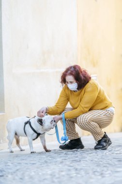 Koruyucu maskeli ve köpekli kadın.