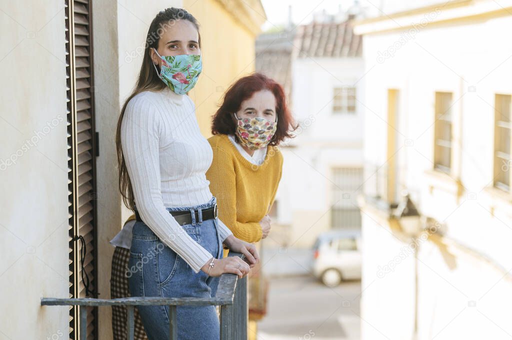 Two women with protective masks in balcony
