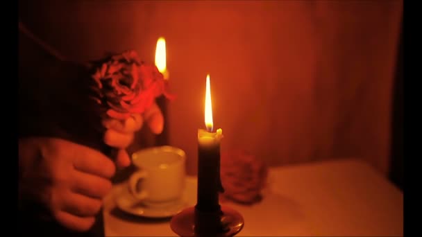 Deux bougies allumées, une tasse de café et un vase aux roses 