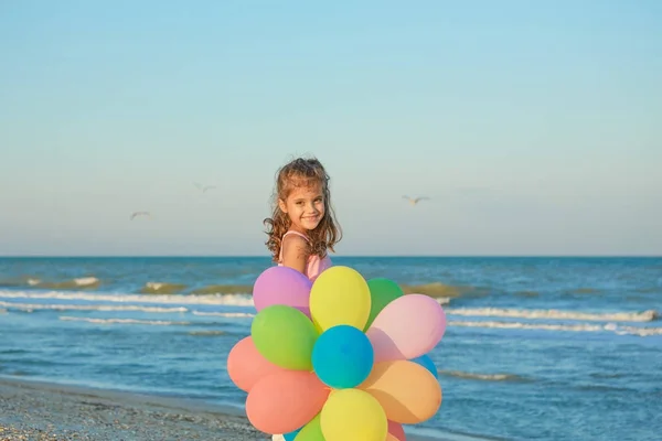 Happy little Girl on the beach with balloons. — Stock Photo, Image