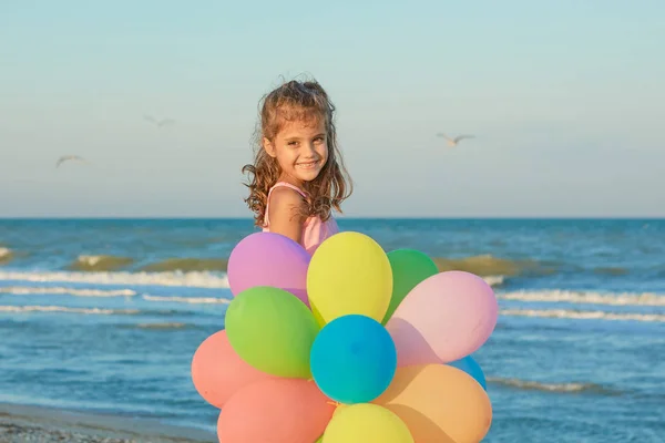 Happy little Girl on the beach with balloons. — Stock Photo, Image