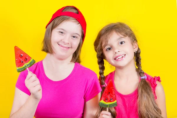 Mädchen Down-Syndrom und kleines Mädchen mit großem Lutscher Stockbild