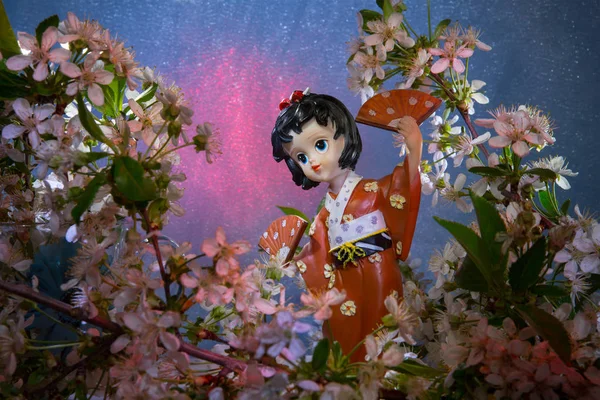 Statuette dancing geisha in the garden. Sakura with decorative lighting — Stock Photo, Image