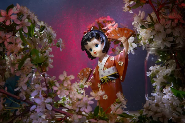 Statuette dancing geisha in the garden. Sakura with decorative lighting — Stock Photo, Image