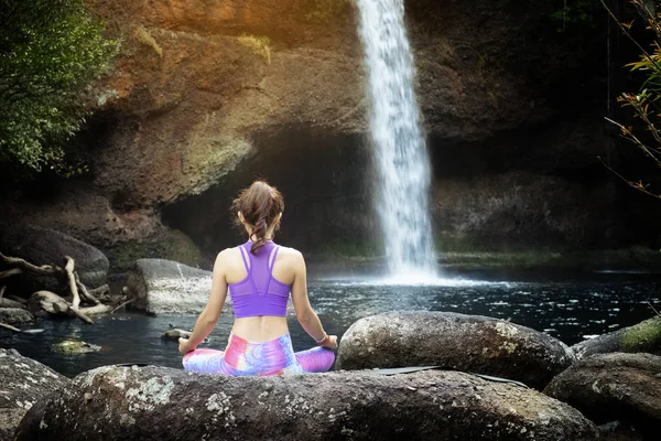 Woman practice yoga in front of waterfall — Stock Photo, Image