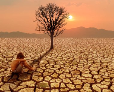Children sitting on crack earth in arid area with dead tree and 