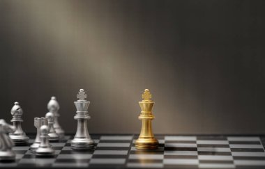 Koyu arkaplanda altın ve gümüş satranç taşları