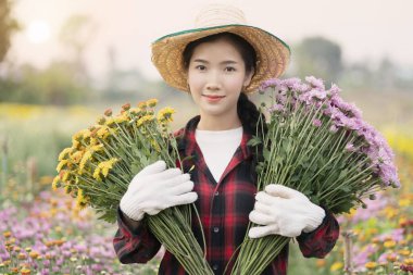 Bahçede çiçek tutan güzel bir kadın.