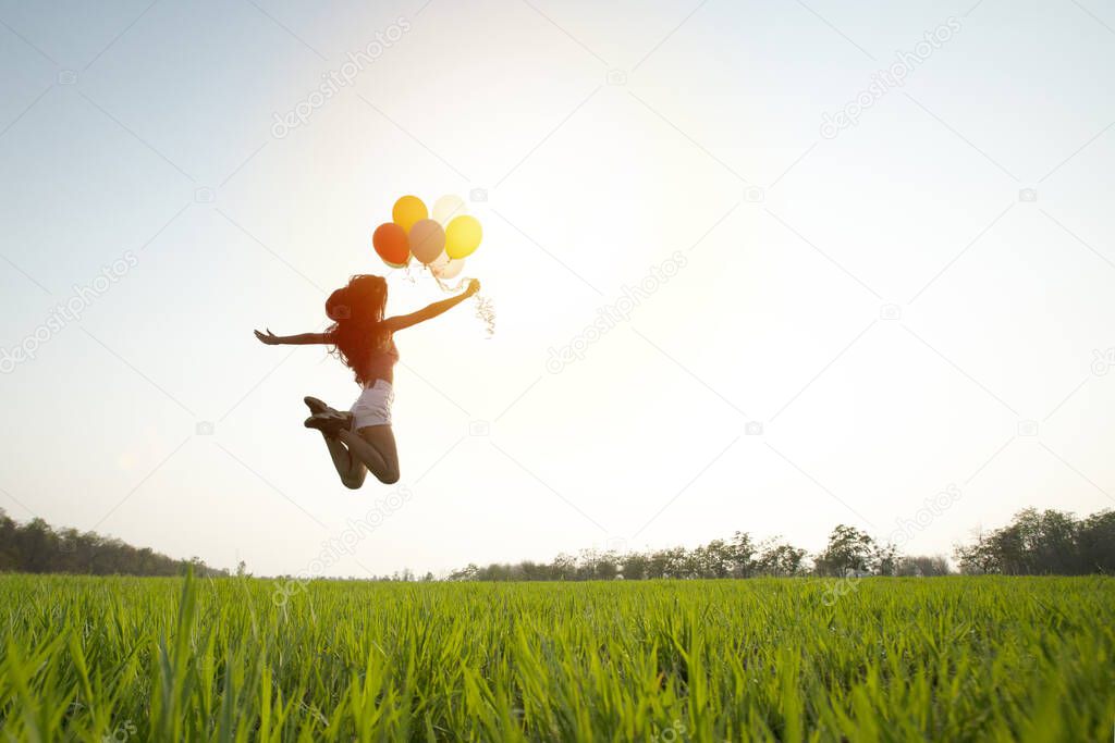 woman jumping colorful balloon on the grass in the park