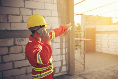 Mühendis sert bir cehennem taşı takıyor ve inşaat alanında akıllı telefon kullanıyor.