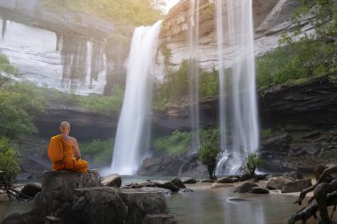 Buda keşişi şelaleyle meditasyon yapıyor.