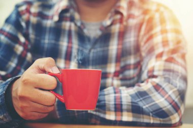 Gevşemek için kırmızı kahve bardağını tutan adamın elini kapat.