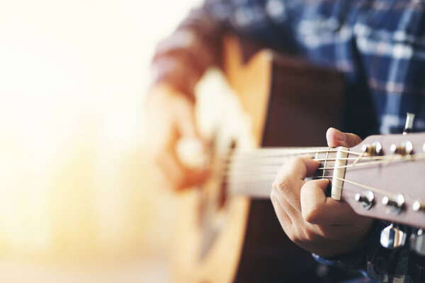 close up hand man playing acoustic guitar