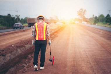Mühendis yolda ölçüm tekeriyle yürüyor.