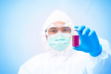 Kişisel koruma ekipmanı ya da PPE 'de çalışan bir doktor. Aşı şişesi, Coronavirus covid-19 salgın konsepti