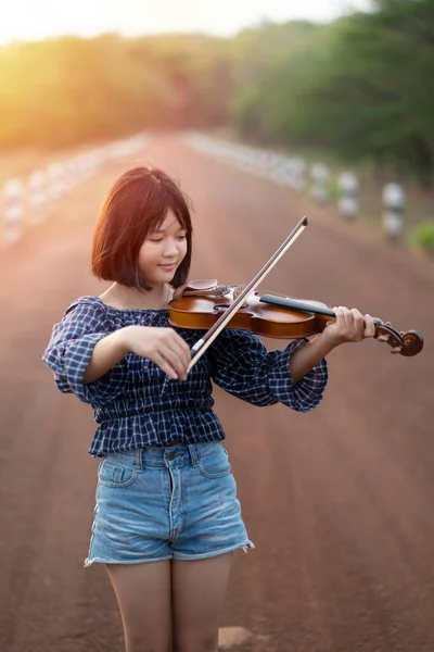 美しい女性が太陽の光を背景にバイオリンを弾く — ストック写真