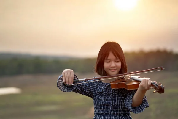 美しい女性が太陽の光を背景にバイオリンを弾く — ストック写真