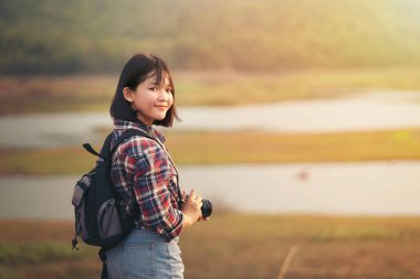 Güneş ışığı geçmişi olan sırt çantalı kadın.