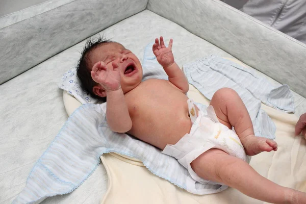 Gråtande nyfödda barn på skötbord. Söt liten flicka eller pojke två veckor gamla. Torr och frisk kropp och hud koncept. Baby plantskola. — Stockfoto