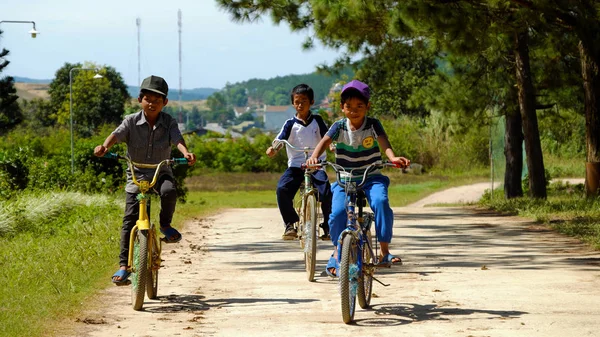 Crianças vietnamitas andam de bicicleta na estrada rural — Fotografia de Stock